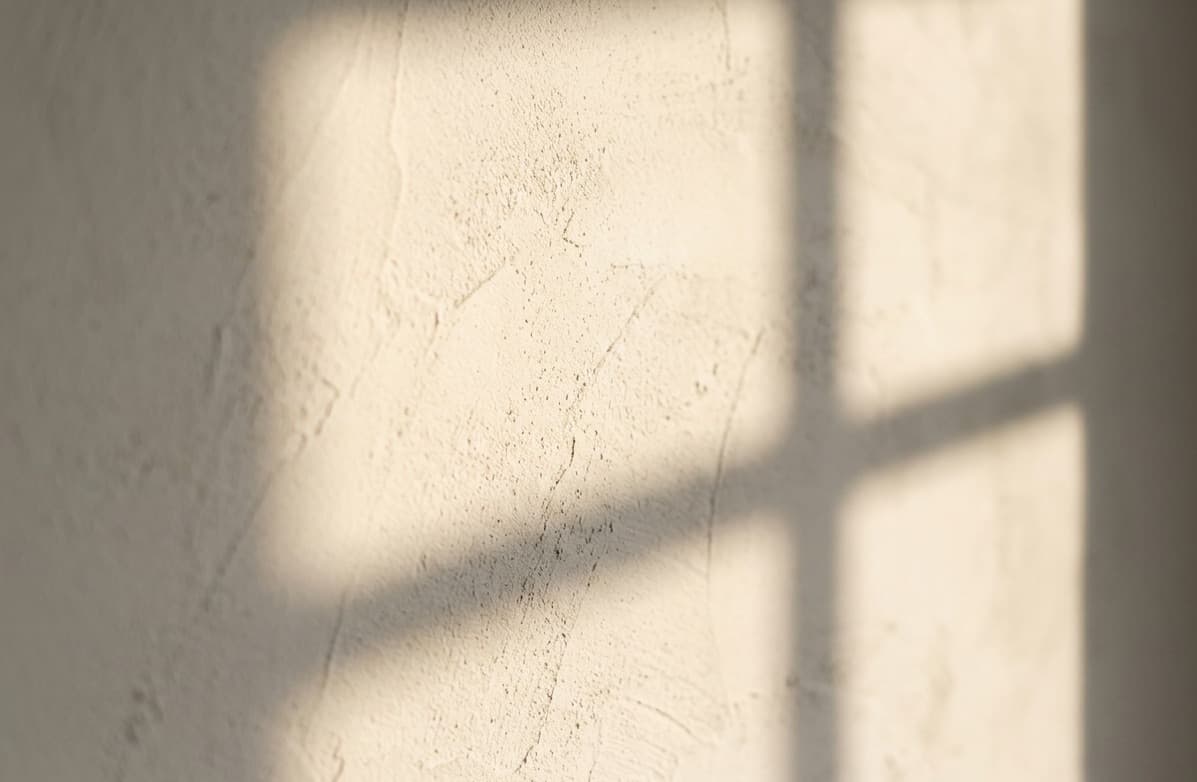 The soft shadow of a window falling across a pale plastered wall